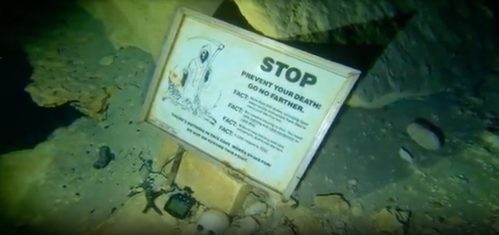 An underwater sign warning divers about dangers, featuring a skeleton and safety facts.